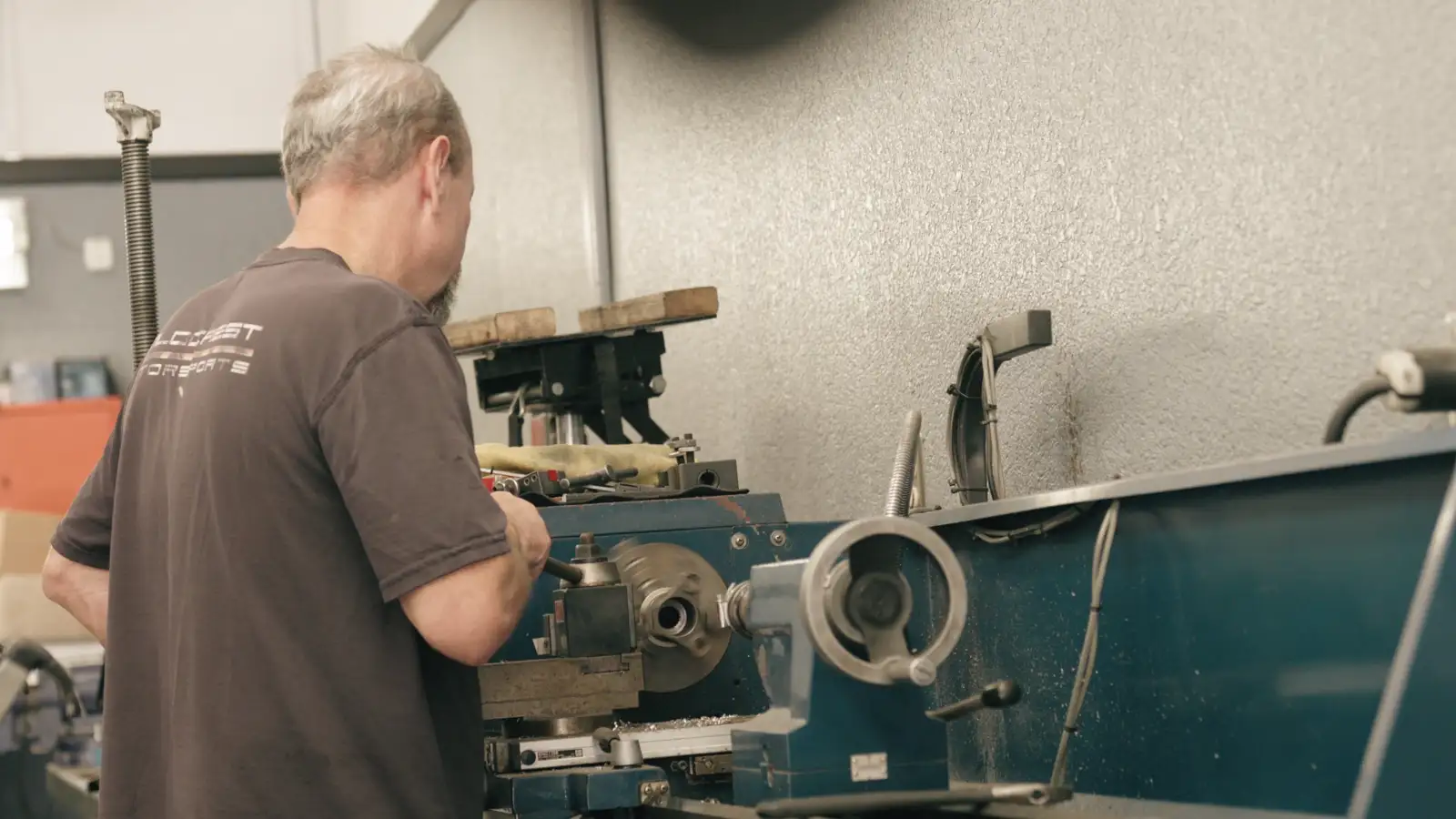 A machinist operating a lathe on a factory floor